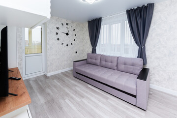 apartment interior. gray sofa in the living room and large wall clock