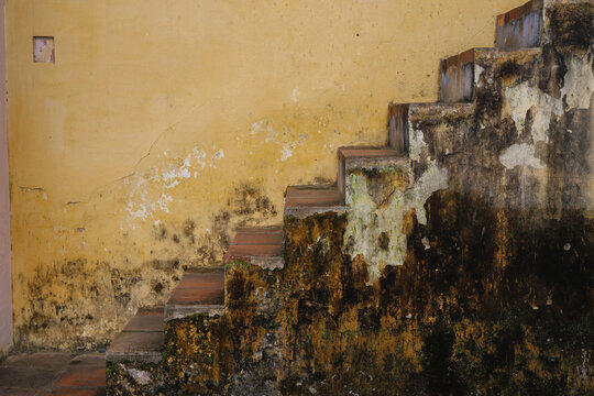 old rustic stairs with lots of patina and soft yellow wall in building in charming town