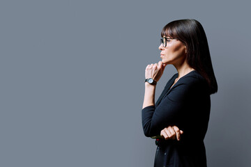 Profile view of serious business woman, gray background, copy space