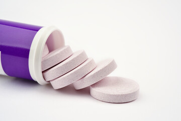 Close up photograph of water soluble indigo blue colour pills, or vitamins in tube, isolated on white background. 