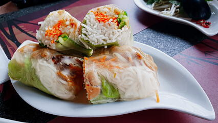 Delicious fresh asian spring rolls filled with glass noodles, carrots, cucumber and herbs, served with tasty dark sauces