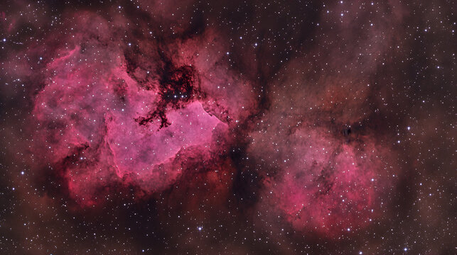 Stunning astrophotography of the Heart Nebula (IC 1805) and Soul Nebula (IC 1848) in Cassiopeia.  Vibrant pink and red hues against a dark starry background. Breathtaking cosmic landscape.