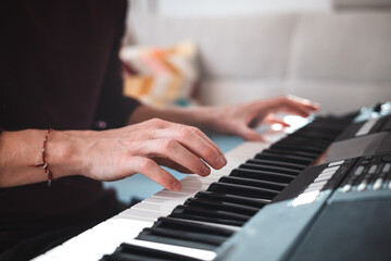 Close-up of a digital keyboard with a hand playing a melody, illuminated by soft natural light. The detailed controls and keys evoke creativity and musical exploration