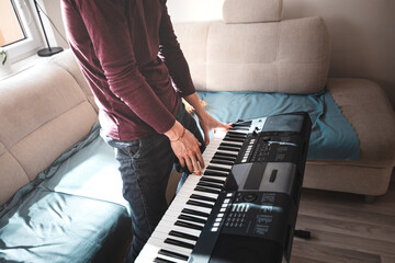 Standing musician playing a digital keyboard in a brightly lit living room, surrounded by cozy...
