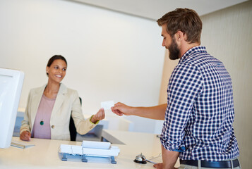 Fototapeta premium Receptionist, man and card for sign in, welcome and help desk with friendly service. Happy people, traveler and employee with room documents, hospitality or holiday with hotel, lodge and vacation