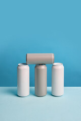 Minimalistic mockup with four aluminum cans arranged on blue background. Simple design for soda water, beer, lemonade, coffee drinks, energy drinks. Fresh and vibrant aesthetic for drink branding.