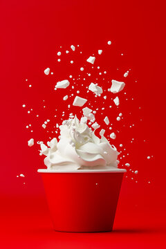 A red cup filled with whipped cream on a red background
