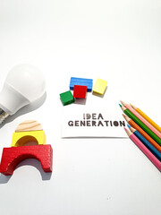 The image shows business concept with light bulb, colored pencils, a pen, geometric blocks, and a card with "IDEA GENERATION" written on it, symbolizing creativity and brainstorming.