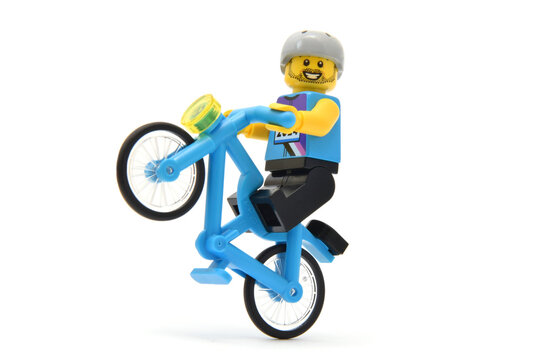 Lego minifigure of stuntman on bicycle or biker is jumped closed up. Editorial illustrative image of popular plastic toy constructor for children.