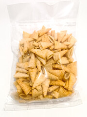 A clear plastic bag containing crispy and flavorful Angry Bite Corn BBQ or Kerepek Topi, a Malaysian snack with cone-shaped chips seasoned with smoky barbecue flavor.