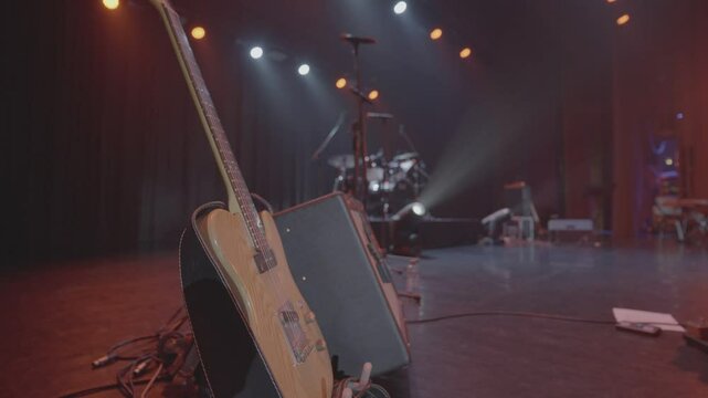 Valmiera, Latvia - November 18, 2024 - An electric guitar rests against an amplifier on a stage, with stage lighting and a drum set in the background, ready for a live music performance.
