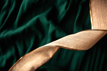 close-up of shiny gold gift wrapping ribbon against a dark green fabric background with copy space available, Christmas themed