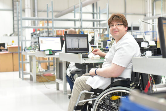 handicapped worker in a wheelchair at a workplace in a electronics manufacturing and assembly factory