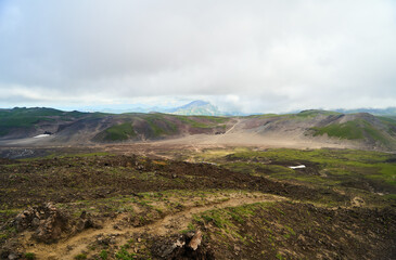 Kamchatka region. A beautiful view of green hills and majestic mountains against a cloudy sky, showcasing natures beauty