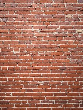 Fototapeta Red brick wall with cracks and chips in a natural setting, natural surroundings, rustic texture.