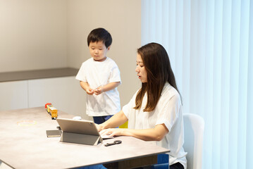 リモート中の母親の横で遊ぶ子供