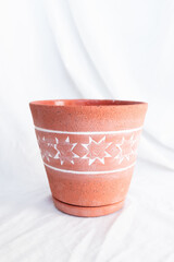Close-up of a terracotta flower pot with a white 8-pointed star pattern, showcasing the textured finish and earthy tones