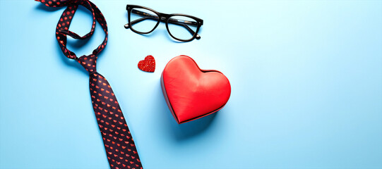 Composition of stylish necktie, watch, gift box, glasses, mustaches, and paper hearts, framed in heart cutout on soft blue background.