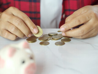 Hand counting coins for saving money with piggy bank on table. Finance business concept. Copy space.
