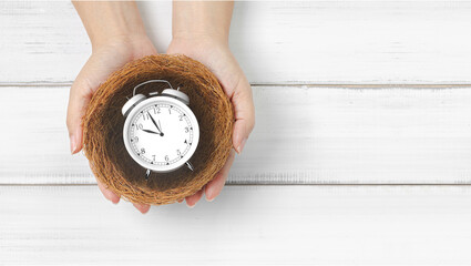 Time Management and Punctuality: Hands Holding Classic Alarm Clock in a Nest