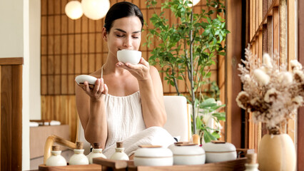 A young woman enjoys the aroma of essential oils in a tropical setting. Aromatherapy, spa and...