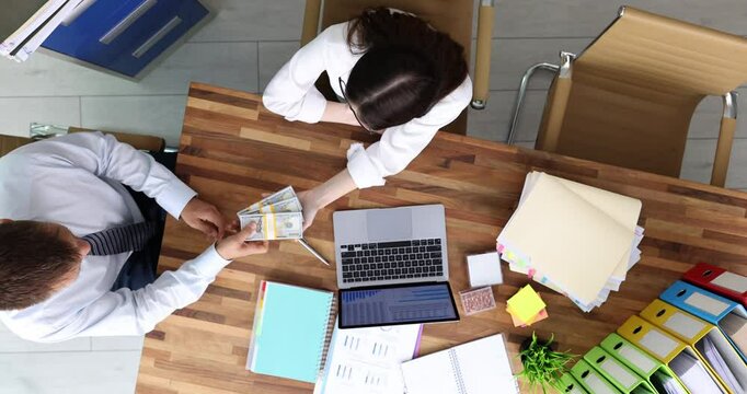 Woman extends hand to accept stacks of dollar bills from man. Businessman gives money to businesswoman expressing satisfaction with service