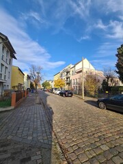 eine Strasse mit blauem Himmel, Bürgersteig und Wohngebäuden in Berlin Friedrichshagen