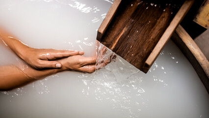 Close-up of a woman's hands touching powdery white water in a Japanese bath. A serene spa moment, perfect for relaxation, wellness, and peaceful retreat concepts.