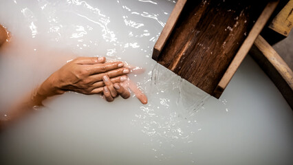 Close-up of a woman's hands touching powdery white water in a Japanese bath. A serene spa moment, perfect for relaxation, wellness, and peaceful retreat concepts.