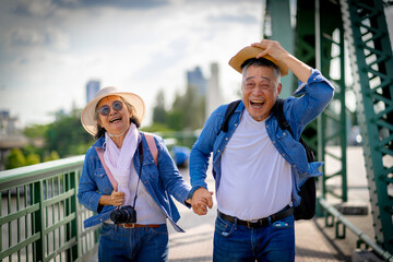 Asian retired couple happily hang out together in city full people city full buildings in capital...