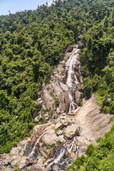 A breathtaking waterfall elegantly cascading through a dense, vibrant tropical forest in an idyllic natural setting
