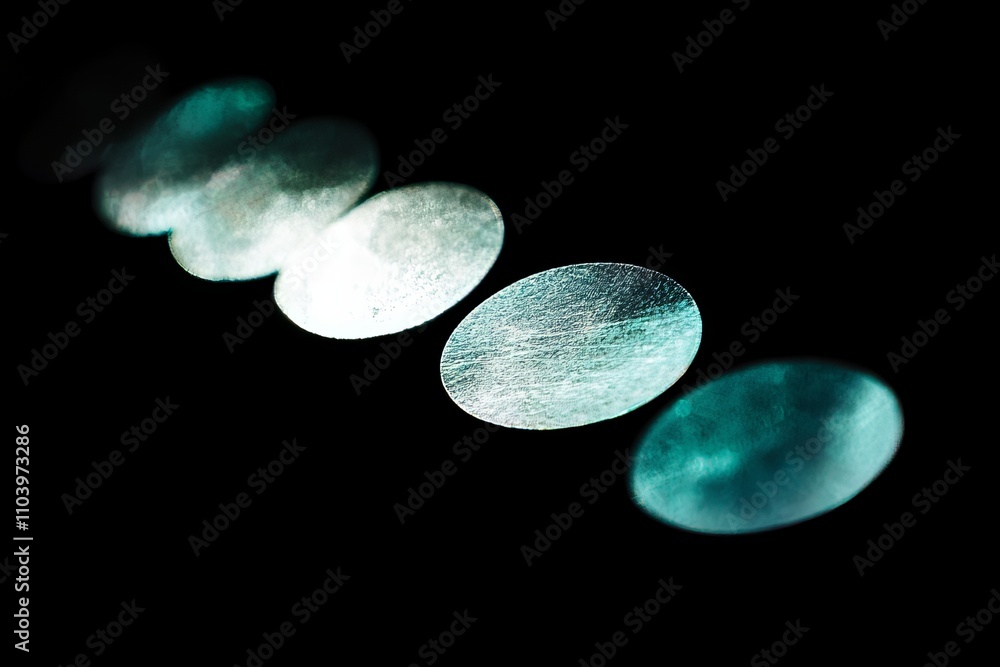 Poster abstract close-up of shiny oval shapes with unique textures against a dark background, showcasing re