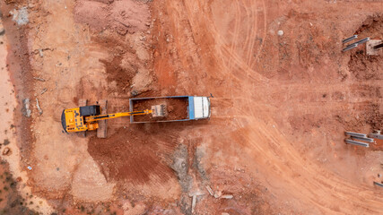 Aerial view road motor grader flatting dirt road surface, Motor grader road construction grader industrial machine construction site new road, Aerial view group excavator working on construction site.