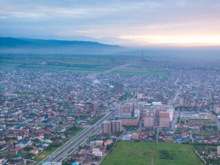City landscape. Evening view from a drone of the city during sunset, mountains on the background....