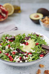 A plate with green rocket salad with pomegranate and avocado	
