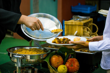 The chef, the cook puts freshly cooked food on the plate. Food tray Stainless steel buffet container. Tables set at a banquet. A fruit and vegetable composition. Fresh fruits, vegetables, fish, salat.