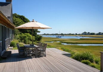 Scenic Waterfront Patio with Dining Table, Umbrella, and Lush Green Landscape Overlooking Calm Water in Bright Sunny Day