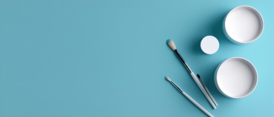 The image shows three white paintbrushes lying on a light blue background. On the left side of the image, there is a small white bowl with a black handle and a white lid.