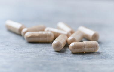 Reishi capsules. Concept for a healthy dietary supplementation. Wooden background. Soft focus. Close up.	