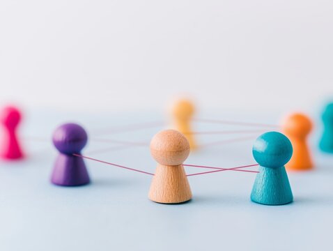Minimalist social network concept multicolored wooden pawns linked together connections relationship structure leadership teamwork unity colorful