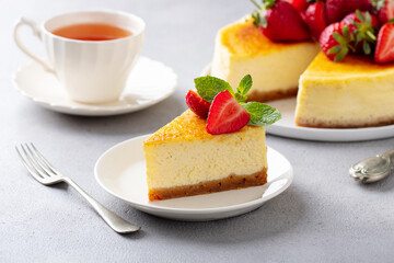 Cheesecake dessert with fresh strawberries and cup of tea. Grey background. Close up.