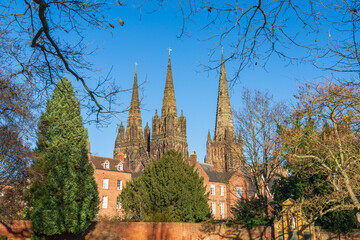 Three spires of Lichfield Cathedral towering over buildings