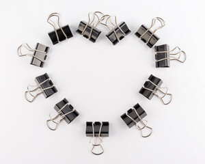 Black binder clips on a white background. Heart of binder clips.