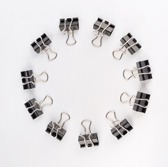 Black binder clips on a white background. Ring of binder clips.