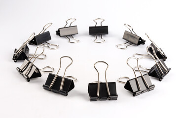Black binder clips on a white background. Ring of binder clips.