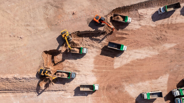Aerial view road motor grader flatting dirt road surface, Motor grader road construction grader industrial machine construction site new road, Aerial view group excavator working on construction site.