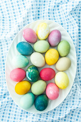 Multi-colored Easter eggs in an oval dish on a blue tablecloth, Happy Easter holiday