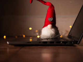 Christmas gnome on laptop with with twinkling lights background bokeh