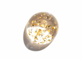 Transparent egg with gold leaf flakes on white background - minimalist artistic concept of luxury and elegance