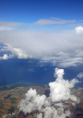 Obraz premium Aerial view of the coast with sea and white clouds from a flying plane